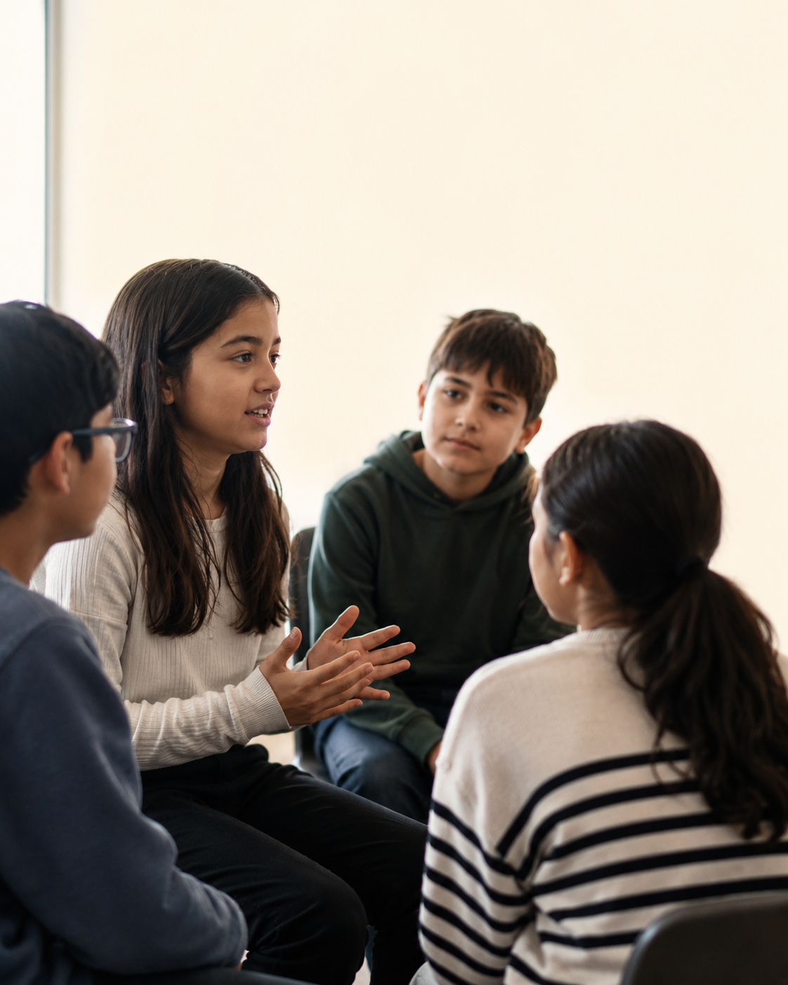 A group of kids sitting together, one gesturing mid-conversation while the others listen